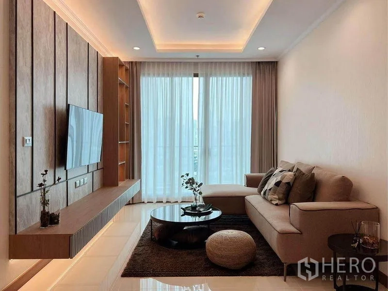 คอนโด ให้เช่าในWatthana, Bangkok - โซนนั่งเล่นอบอุ่น โซฟาเข้ามุม โต๊ะกลางกลม พรม และผ้าม่านเต็มความสูงเปิดสู่ระเบียง