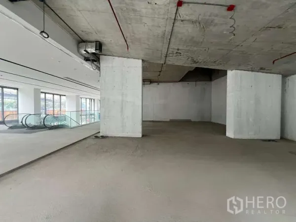 零售空间 出租 - 靠近扶梯与落地窗的开放式商铺，未完成的混凝土顶与结构立柱