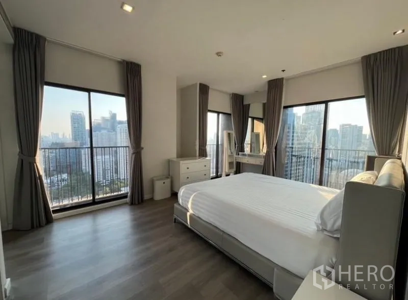 Condominium for rent in Bangkok - Corner bedroom with multiple glass doors to balconies, dressing table and panoramic skyline views.