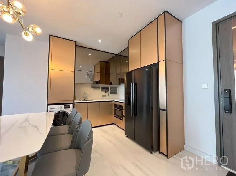 Condominium for rent or sale in Sathon, Bangkok - Modern L-shaped kitchen with premium cabinetry, black double-door fridge and washer.