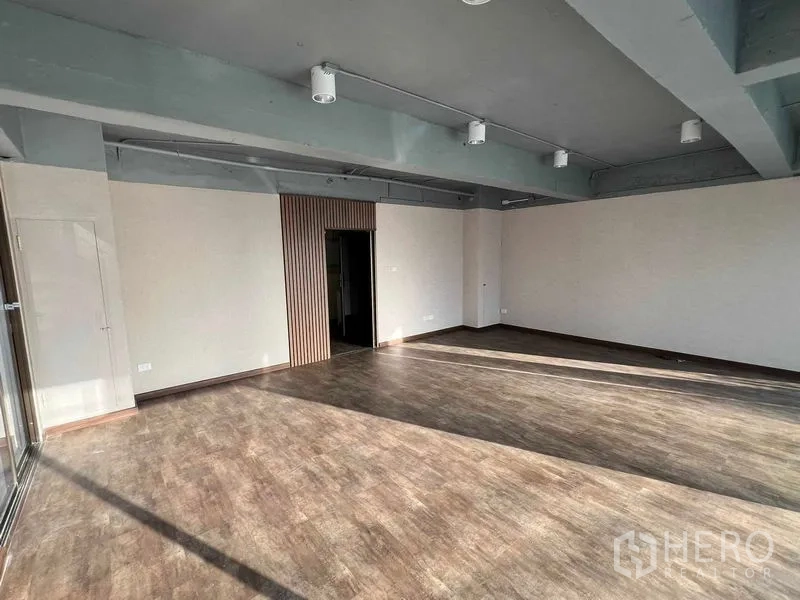 Office Space for rent or sale in Suan Luang, Bangkok - Spacious office floor with wood-look vinyl, ceiling spotlights, and doorway to a private room.