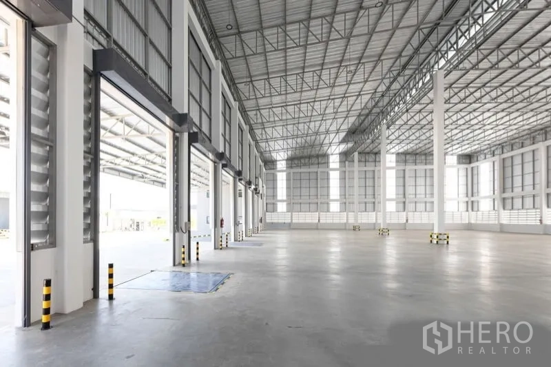 Warehouse for rent in Bang Bo, Samut Prakan - Interior view toward open dock doors and a covered loading apron with safety bollards.