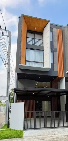 联排别墅 出租在Suan Luang, Bangkok - 现代3.5层角落联排别墅外立面，带遮棚车位与木质格栅。