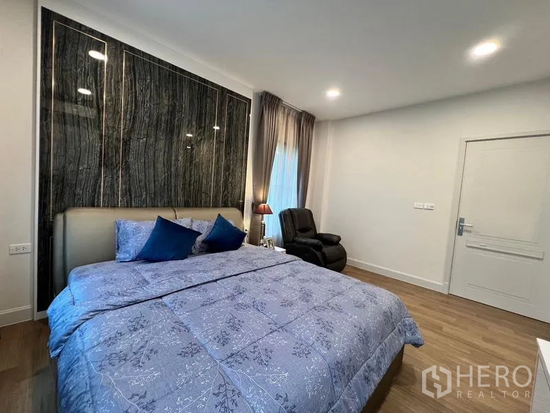 Detached House for rent or sale in Saphan Sung, Bangkok - Bedroom from another angle showing the feature wall, bed and doorway.