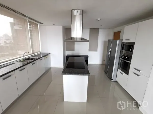 公寓 出租在Watthana, Bangkok - 现代白色厨房，带花岗岩岛台灶台、抽油烟机，不锈钢家电与大窗景。