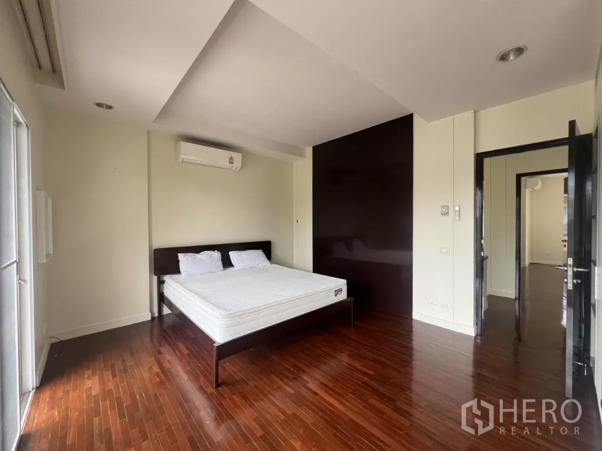 Detached House for rent in Wang Thonglang, Bangkok - Second bedroom with wooden flooring, AC and neutral walls.