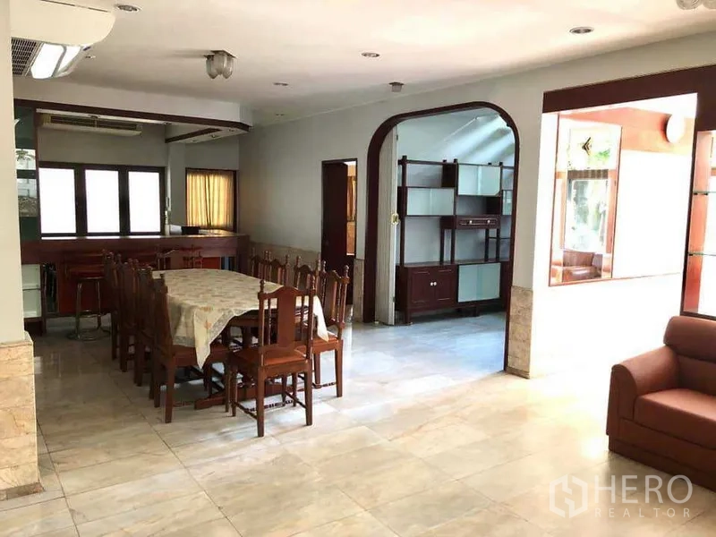 Detached House for rent in Phra Khanong, Bangkok - Open‑plan dining area beside the kitchen with wooden dining set and tiled floor.