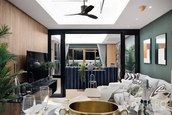 Condominium for rent in Bang Rak, Bangkok - View across the lounge with TV console and ceiling fan toward a blue bar nook and large windows with curtains.