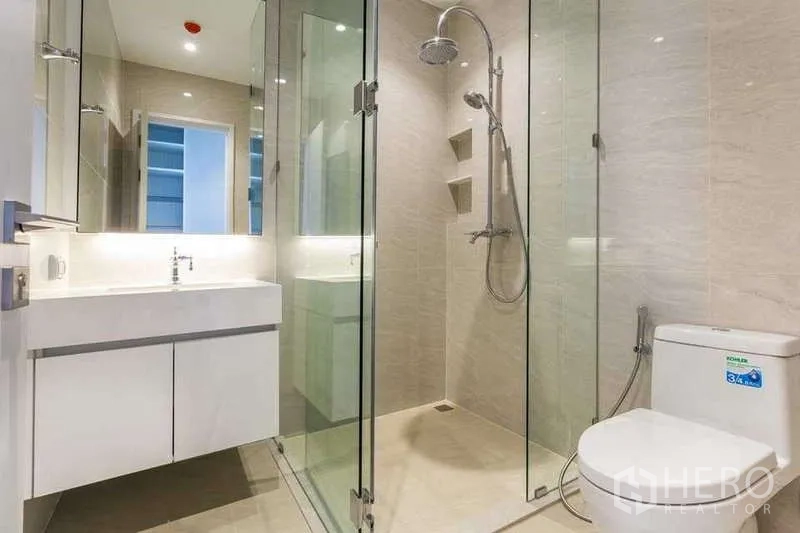 Condominium for rent in Pathum Wan, Bangkok - Bathroom with glass shower enclosure, rain shower and white vanity.