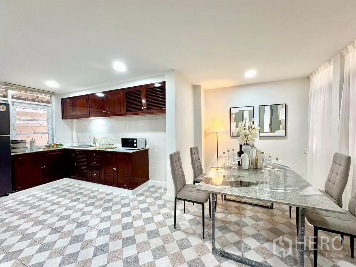 Detached House for rent in Huai Khwang, Bangkok - Kitchen and dining zone with dark wood cabinets and stone dining table