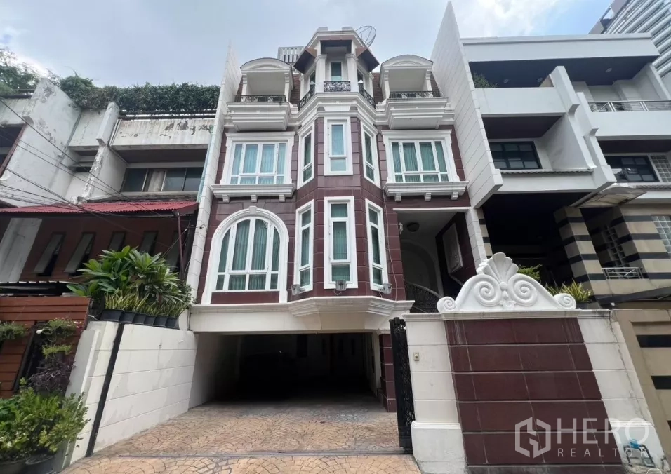 Townhouse for sale in Watthana, Bangkok - Multi-level townhouse facade with arched windows, gated driveway and parking in Watthana, Bangkok.