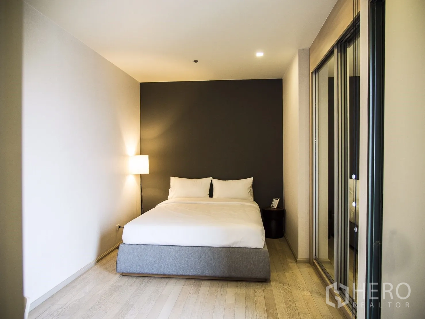 Condominium for rent in Watthana, Bangkok - Secondary bedroom with queen bed, mirrored wardrobe and warm ambient lighting.