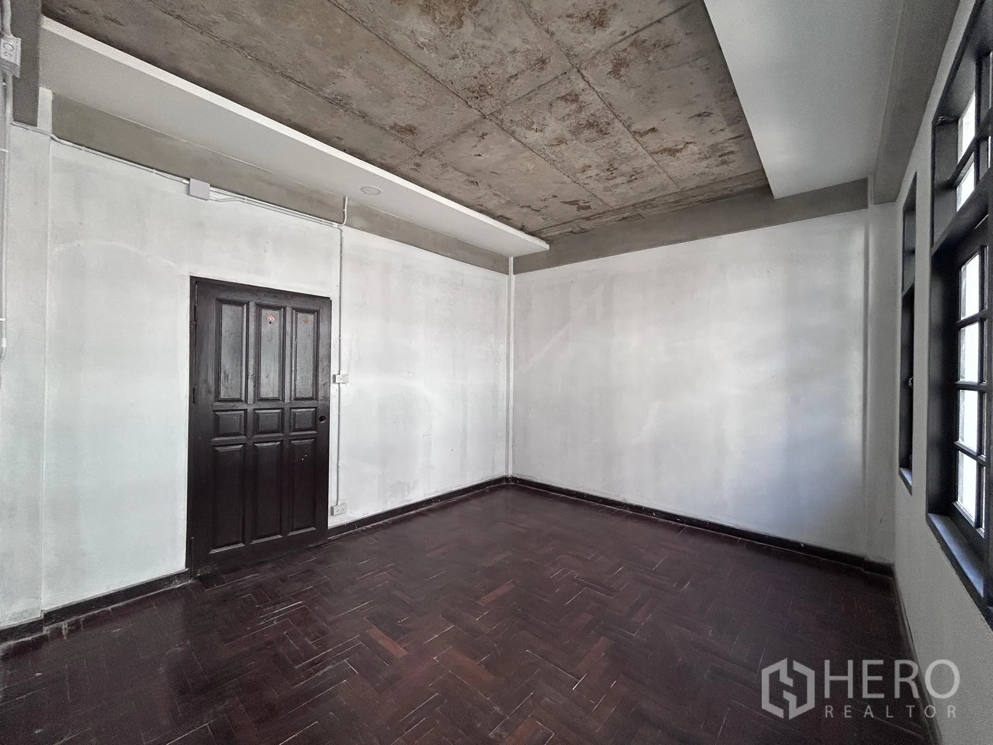 家庭办公室 for rent or sale in Watthana, Bangkok - 深色人字形木地板房，带窗与实木门。