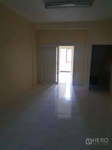 Retail Space for rent in Khlong Toei, Bangkok - Interior room with cream walls, tiled floor and a sliding glass door opening to a brighter area.