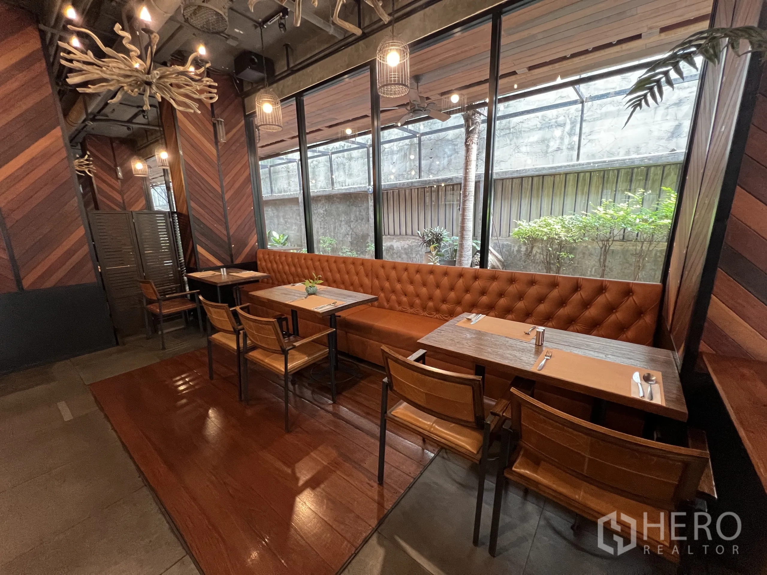 Retail Space for rent in Watthana, Bangkok - Window-side booth seating with tufted leather banquette, small tables, and chevron wood accents.