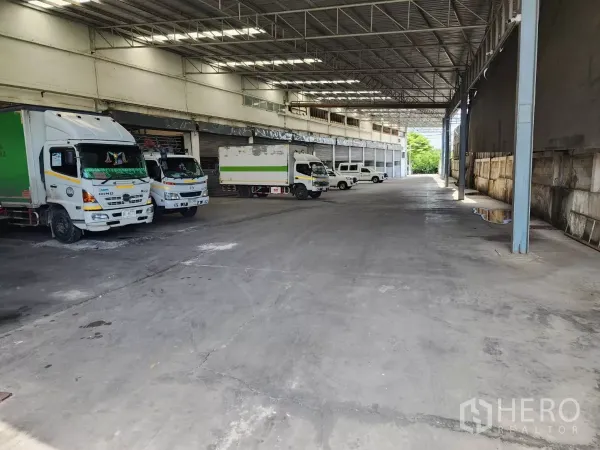 Factory for rent in Mueang Samut Sakhon, Samut Sakhon - Covered truck bays with multiple delivery trucks parked beneath a high canopy.
