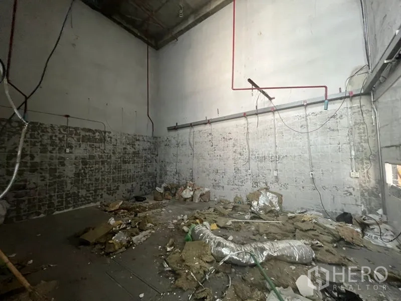 Retail Space for rent in Sathon, Bangkok - Rear storage area with unfinished walls, visible wiring and debris in a high-ceiling shop unit.
