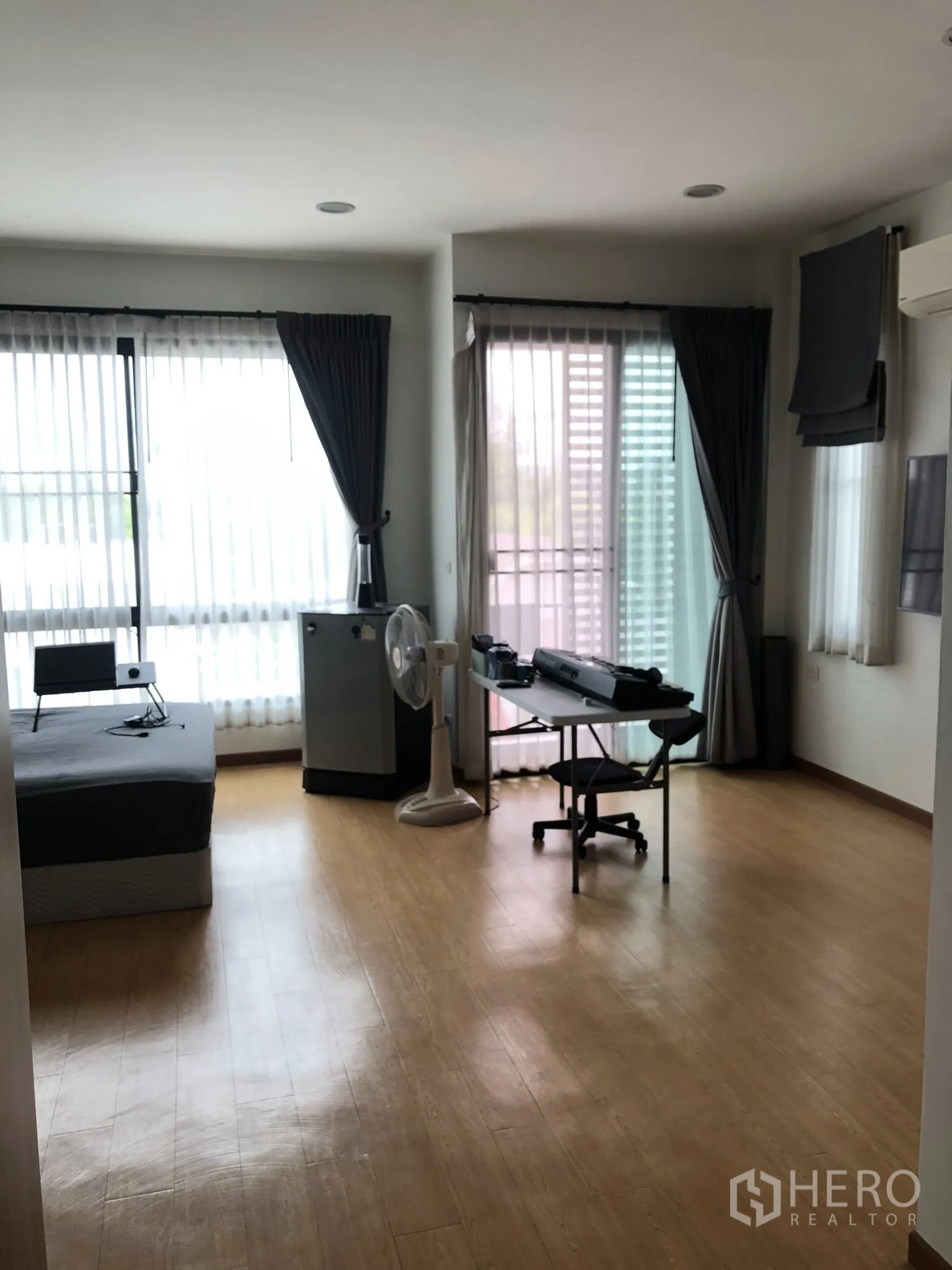 Townhouse for sale in Phra Khanong, Bangkok - Corner bedroom or home office with wood flooring, floor-to-ceiling windows and balcony access.