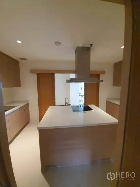 Condominium for rent or sale in Sathon, Bangkok - Modern enclosed kitchen with island cooktop, stainless range hood, and light wood cabinetry.
