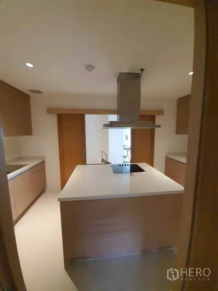 Condominium for rent or sale in Sathon, Bangkok - Modern enclosed kitchen with island cooktop, stainless range hood, and light wood cabinetry.
