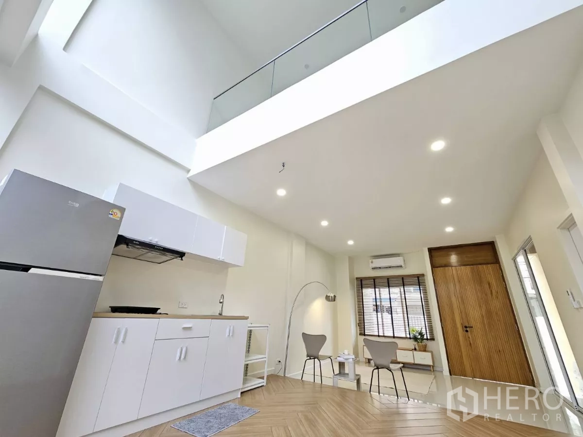 Townhouse for sale in Lat Phrao, Bangkok - Open-plan living and pantry beneath a soaring 6.15 m ceiling with tall windows.