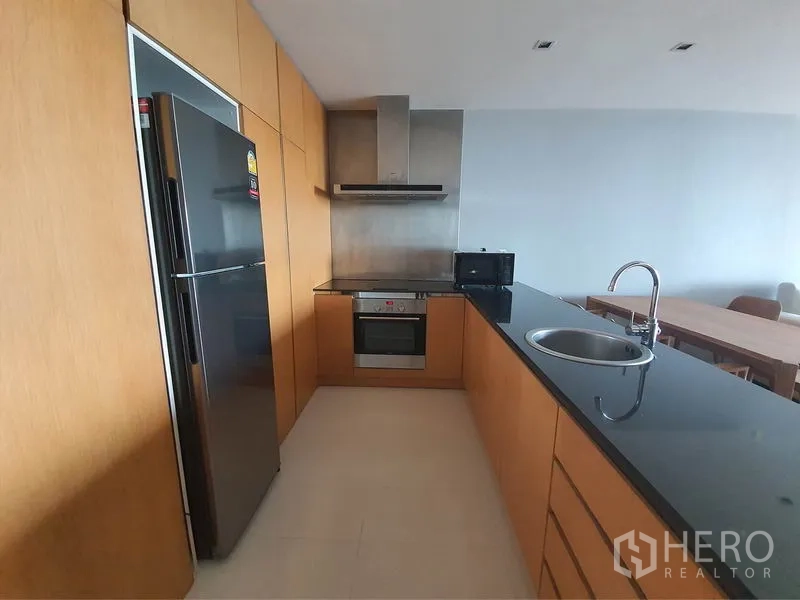 公寓 出租在Yan Nawa, Bangkok - 现代厨房，黑色花岗岩台面，嵌入式烤箱、抽油烟机与不锈钢冰箱。