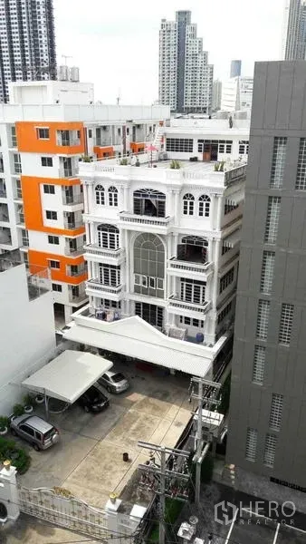 Office Space for rent in Khlong San, Bangkok - Aerial view of the stand-alone white office amid city buildings with on-site parking and the Bangkok skyline.