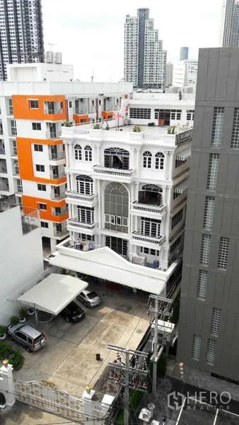 Office Space for rent in Khlong San, Bangkok - Aerial view of the stand-alone white office amid city buildings with on-site parking and the Bangkok skyline.