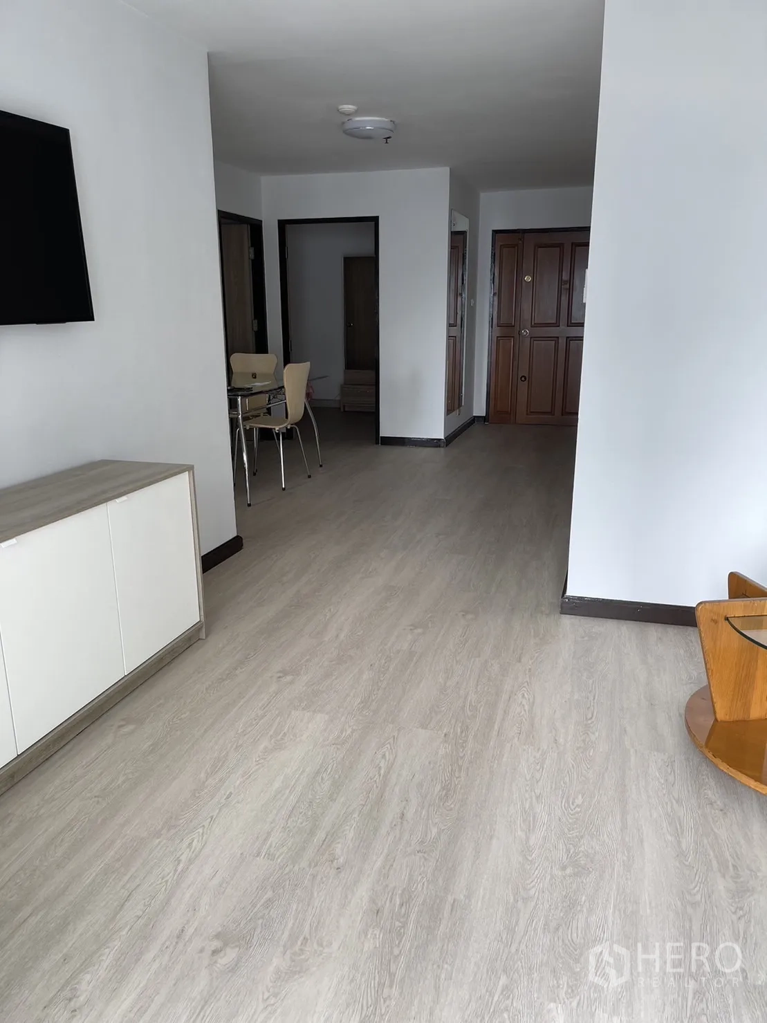 Condominium for rent or sale in Watthana, Bangkok - Spacious corridor and living area with light floors leading to the entry door.