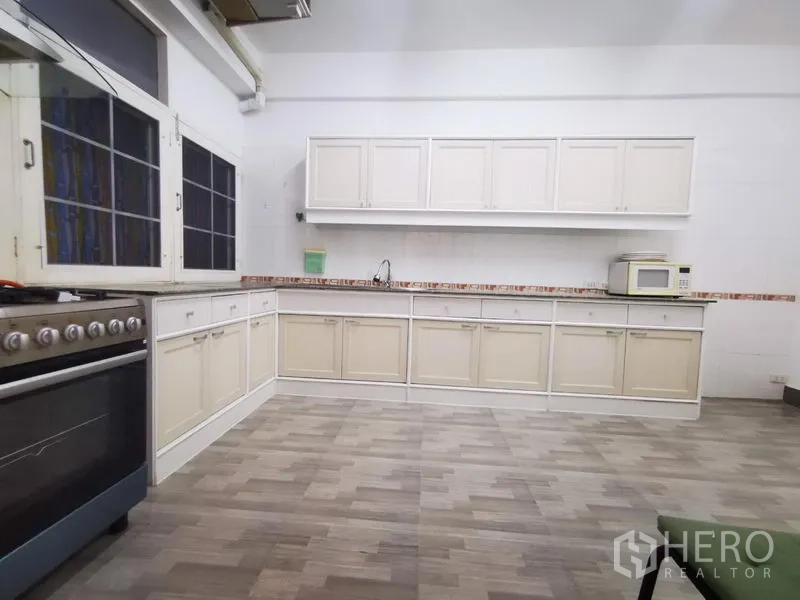 Apartment for rent in Khlong Toei, Bangkok - Large kitchen with long white cabinetry, gas range and tiled flooring.