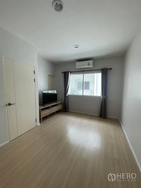 Townhouse for rent in Suan Luang, Bangkok - Spacious multipurpose room with window, air conditioning and TV console.