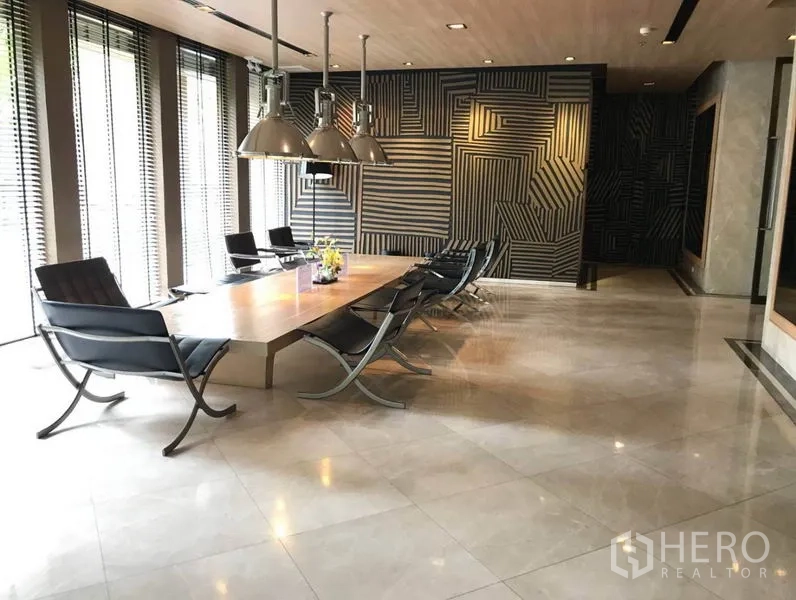 Condominium for rent in Bangkok - Stylish residents’ lounge and meeting room with a long wooden table, modern chairs, and pendant lights.