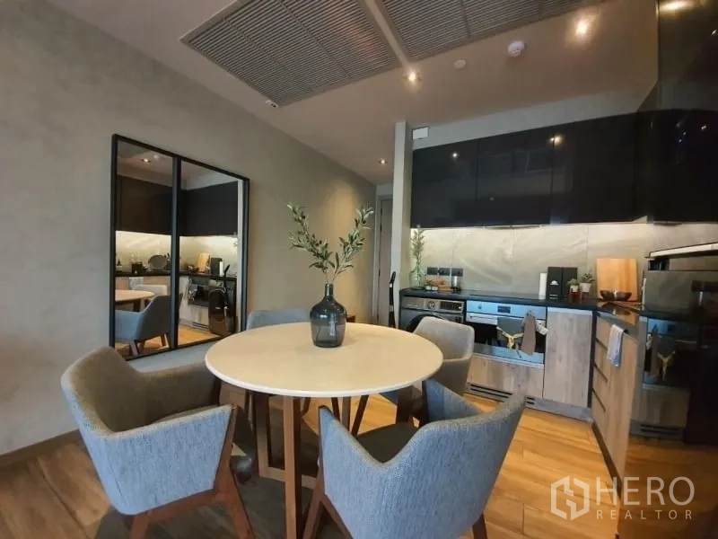 Condominium for rent or sale in Watthana, Bangkok - Cozy dining nook with a round table and four chairs beside the modern kitchen.