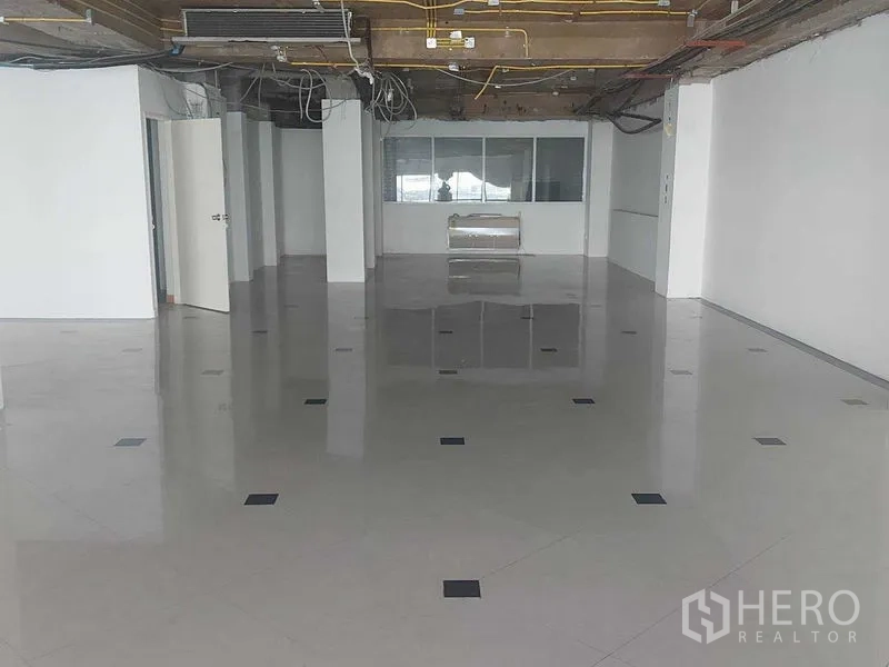 Retail Space for rent in Pathum Wan, Bangkok - Spacious upper floor with polished tiles, exposed ceiling and a partitioned windowed room.