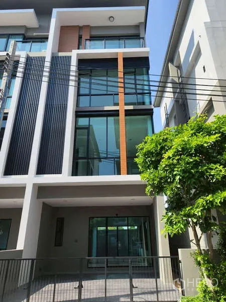 带办公室的家 出租在Bueng Kum, Bangkok - 现代多层联排式商住办公楼外立面，大面积落地玻璃与竖向百叶，前方带围栏车位。