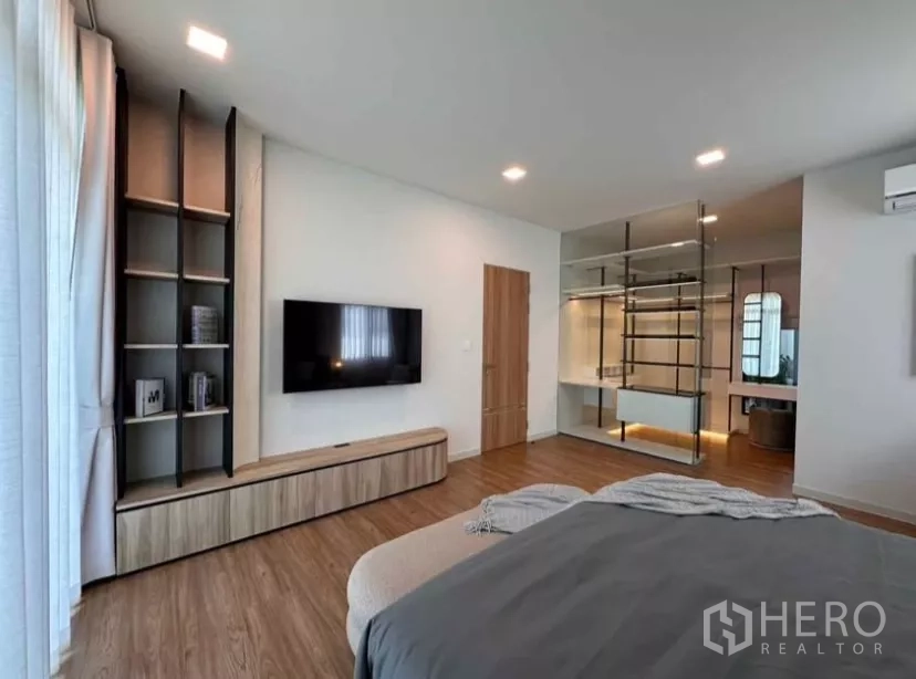 Detached House for rent in Samut Prakan - Master suite view with TV wall, shelving, and glass-partitioned dressing room.