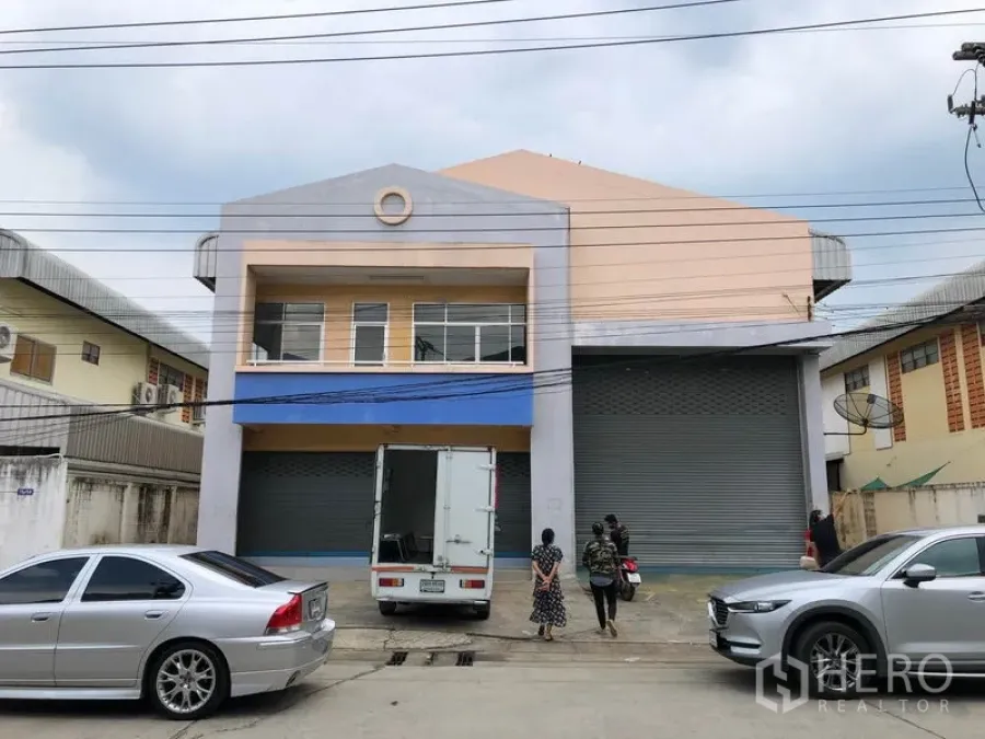 Factory for rent in Pathum Thani - Two-storey factory exterior in Khlong Luang, Pathum Thani with wide roller shutters and truck loading area.