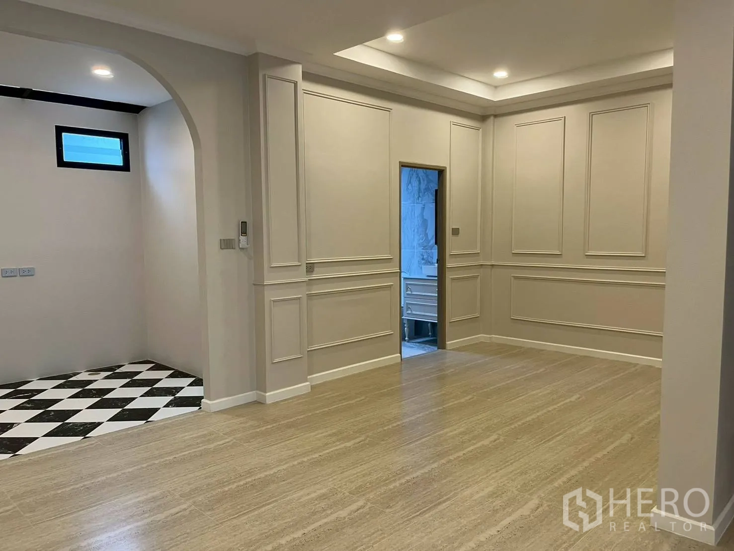 联排别墅 for rent in Khlong Toei, Bangkok - 开放式客厅，与拱形入口的厨房区相连，墙面带线条装饰。