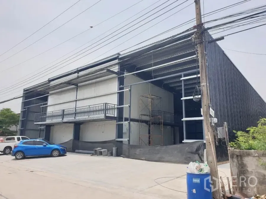 Warehouse for rent in Lam Luk Ka, Pathum Thani - Modern steel-frame warehouse exterior with two-storey office mezzanine and parking area.
