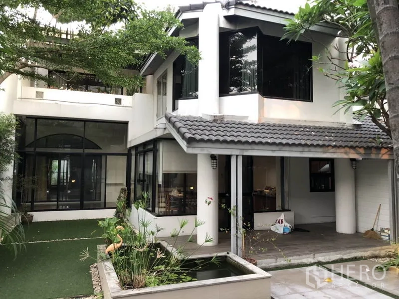 Detached House for rent in Bang Rak, Bangkok - Rear exterior with large corner windows, covered terrace, and a small garden pond.