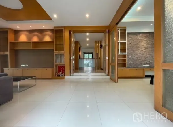 Detached House for rent in Chatuchak, Bangkok - Open-plan living hall with built-in wooden cabinetry and glossy tiled floors.