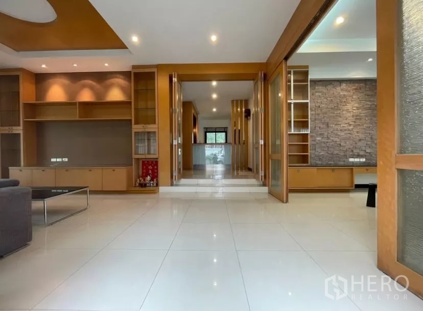 Detached House for rent in Chatuchak, Bangkok - Open-plan living hall with built-in wooden cabinetry and glossy tiled floors.