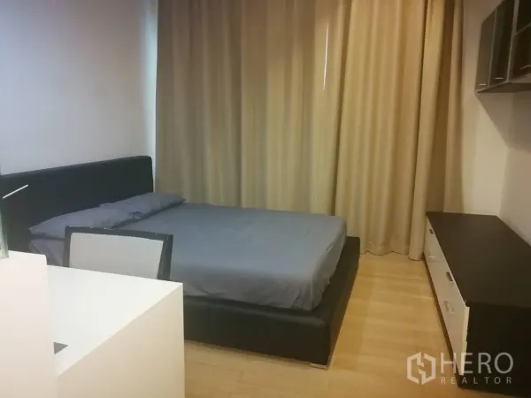 Condominium for rent in Khlong Toei, Bangkok - Bedroom with double bed, work desk, storage cabinet and blackout curtains on wood floors.