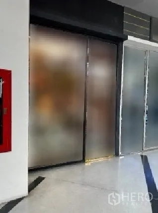 零售空间 出租在Khlong Toei, Bangkok - 室内小型商铺，磨砂玻璃推拉门与抛光地面，走廊设有红色消防柜。