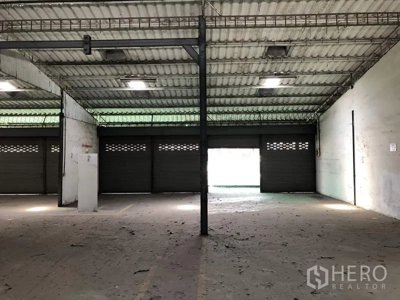 货栈 出租在Khlong Luang, Pathum Thani - 室内朝向多樘卷帘门的视角，便于装卸与通风。