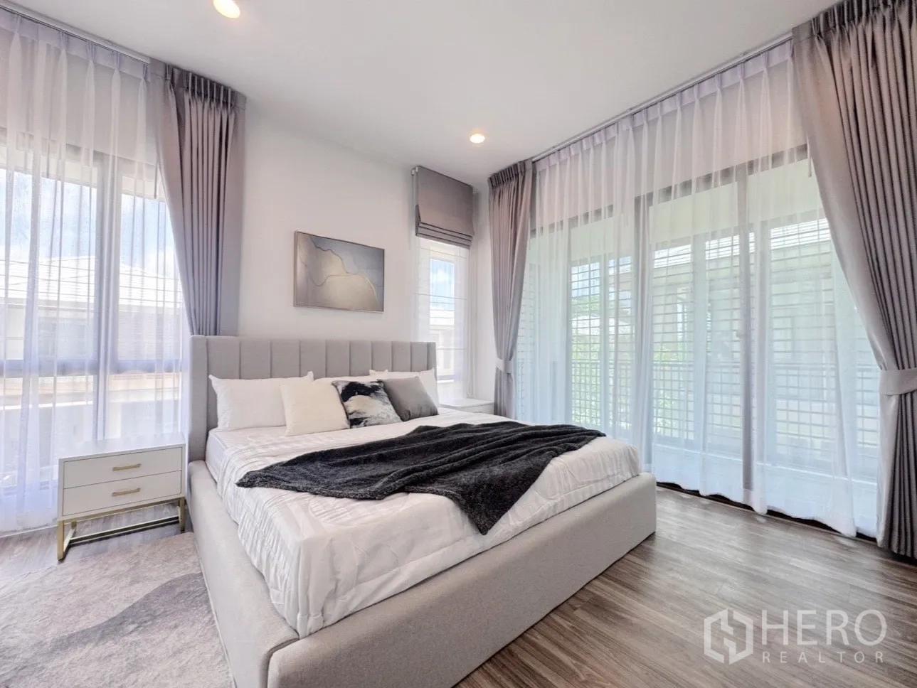 Detached House for rent or sale in Bang Kapi, Bangkok - Master bedroom with a wall of windows, drapes and abundant natural light.