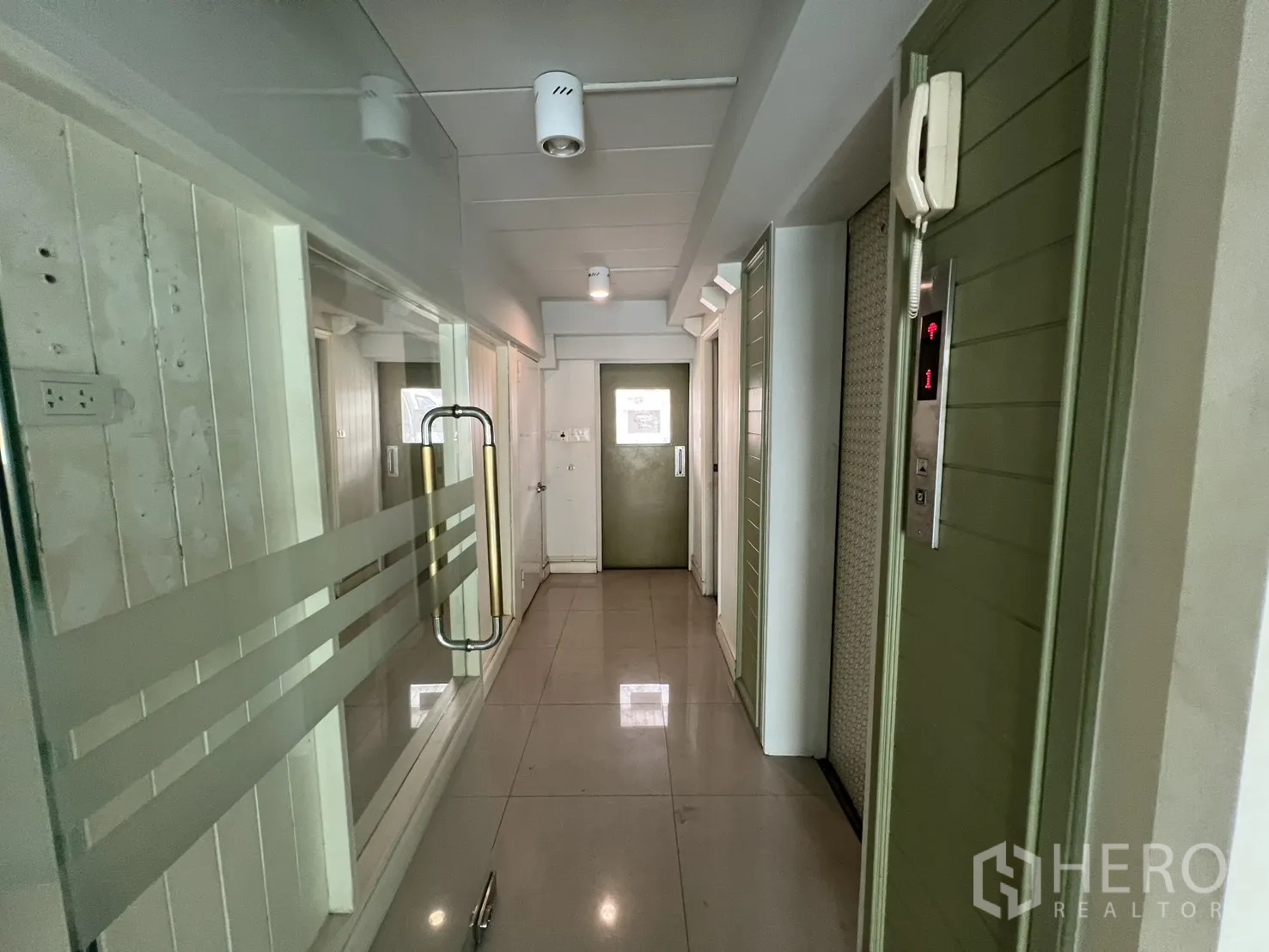 Shophouse for rent in Bang Rak, Bangkok - Interior corridor with glass door, elevator access and ceiling spotlights.
