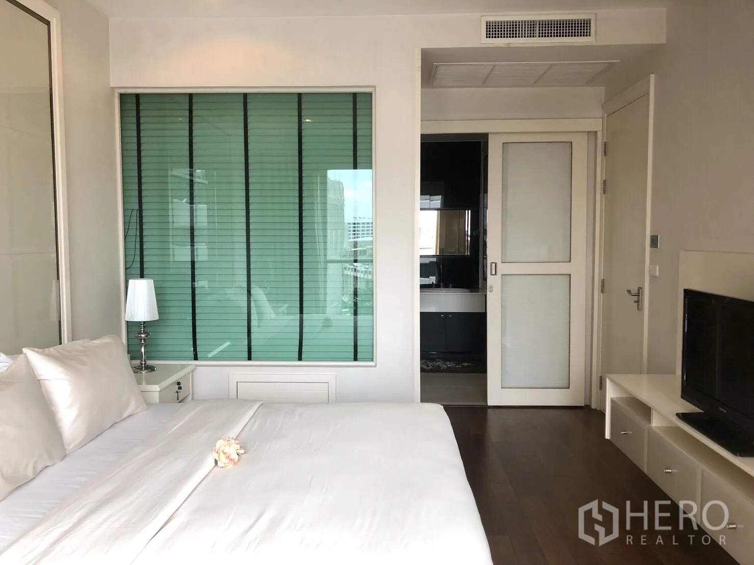 公寓 出租在Pathum Wan, Bangkok - 宽敞卧室，特大床、木地板、电视柜，滑门通往带玻璃隔断的浴室。
