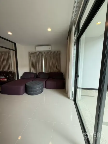 Detached House for rent in Bang Kapi, Bangkok - Family room with large windows, sliding doors, air conditioning, and sectional sofa.