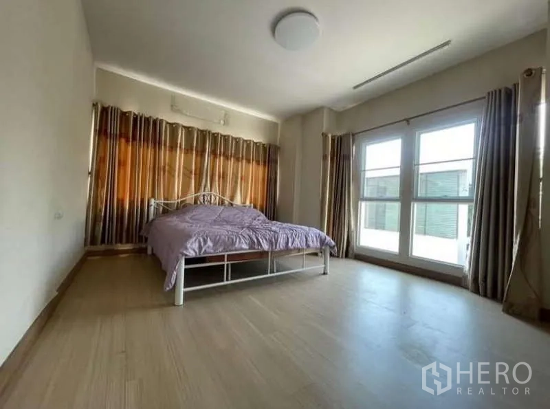 Detached House for rent in Bang Phli, Samut Prakan - Bright secondary bedroom with large windows, curtains and laminate floors.